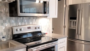 Una cucina moderna con elettrodomestici in acciaio inossidabile, tra cui forno a microonde, forno e frigorifero.