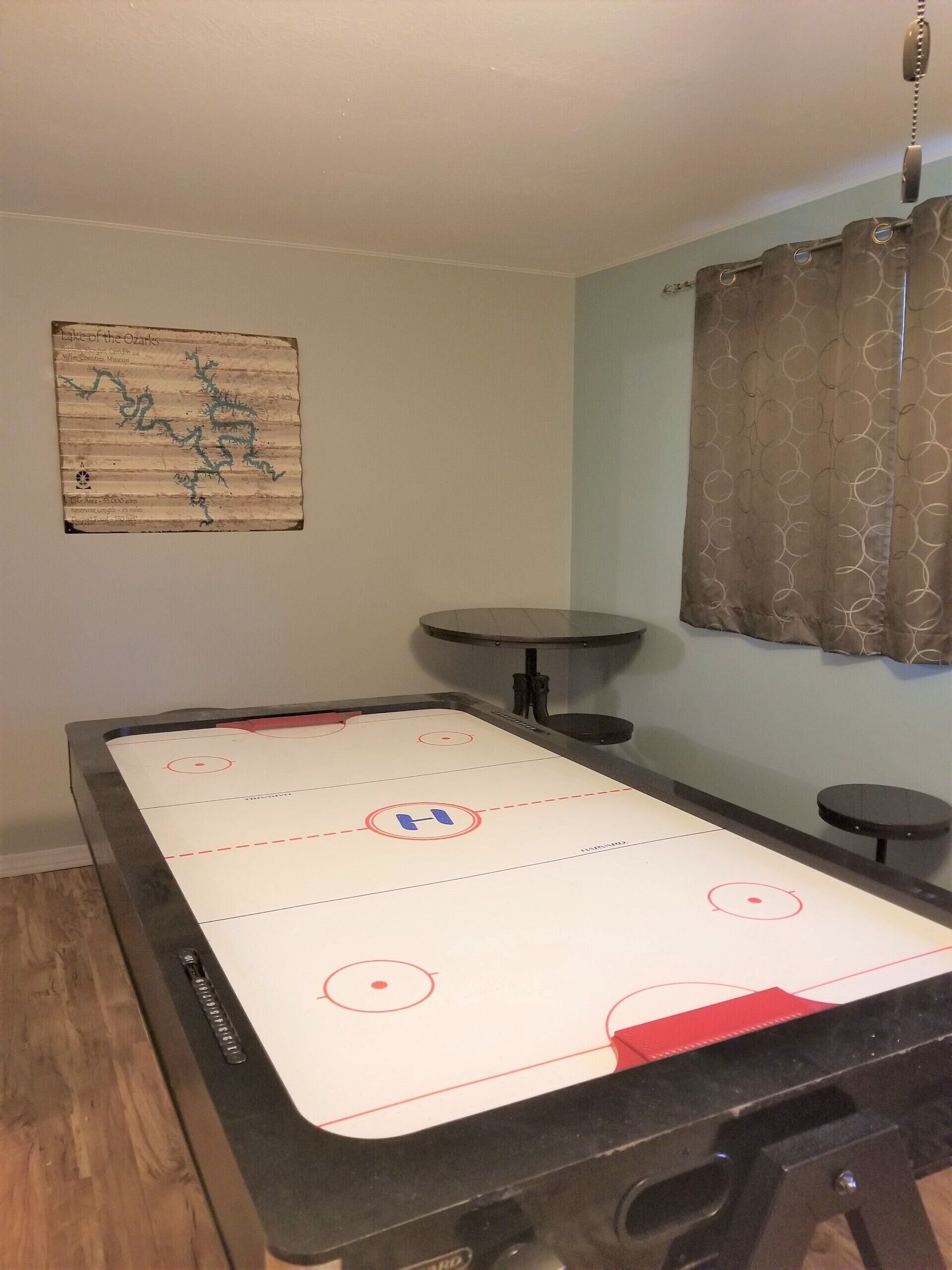A room with a pool table, a poster on the wall, and a window with curtains.