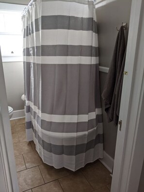 Een bad/douchecombinatie, een haardroger, handdoeken, zeep