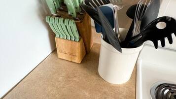 A kitchen counter with a wooden knife block and a white utensil holder.