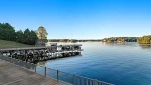 A wooden dock extending into a calm lake, surrounded by trees and a clear sky. - Smith Mountain Lake Condo with Main Channel Views (Moneta)