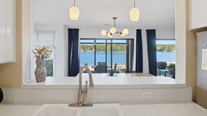 A modern kitchen with a large window, a vase with flowers, and a view of the sea. - Smith Mountain Lake Condo with Main Channel Views (Moneta)