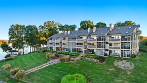 A multi-story hotel with balconies, a well-maintained lawn, and a view of the water. - Smith Mountain Lake Condo with Main Channel Views (Moneta)