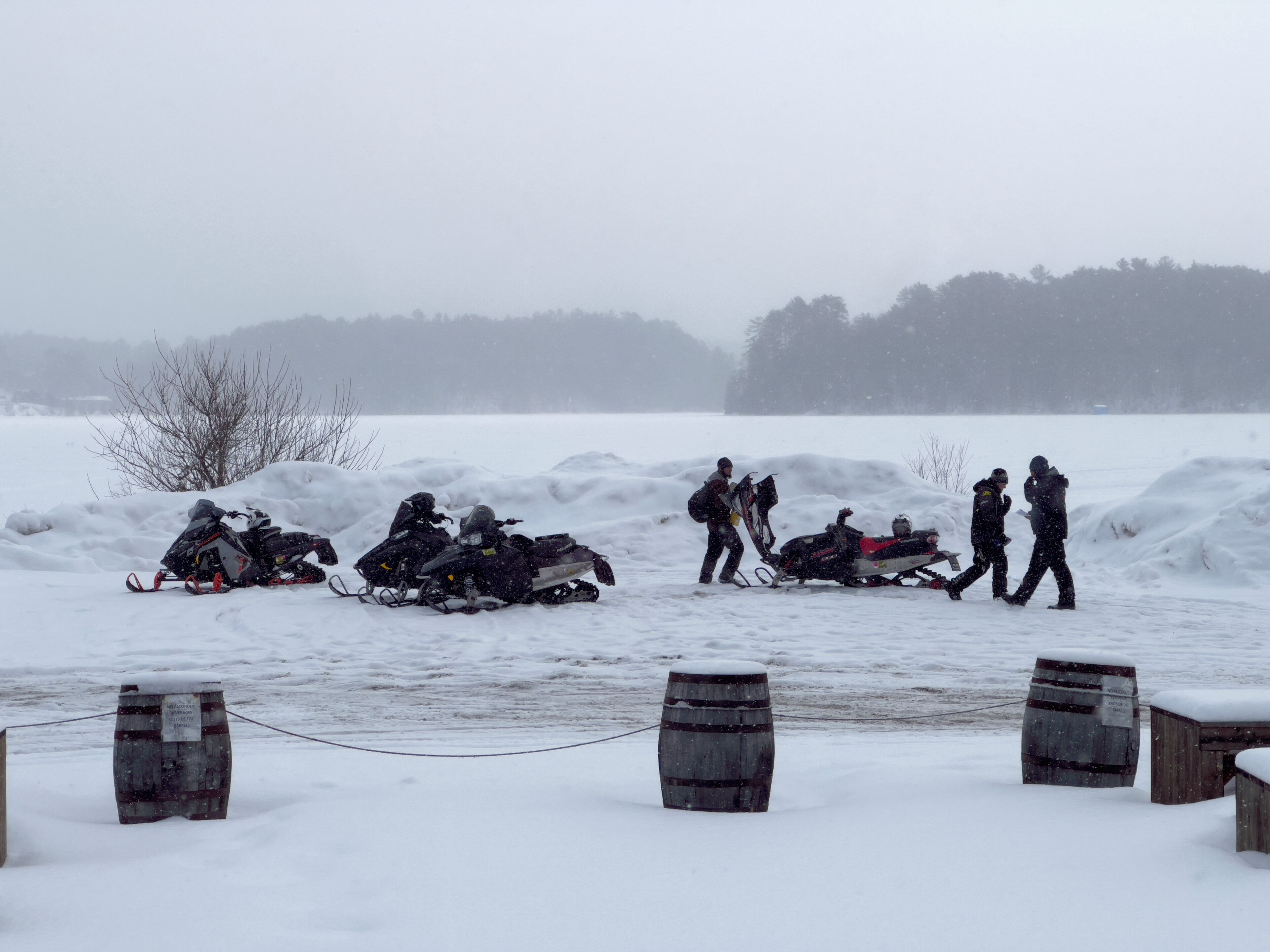 A snowy landscape with snowmobiles and people.