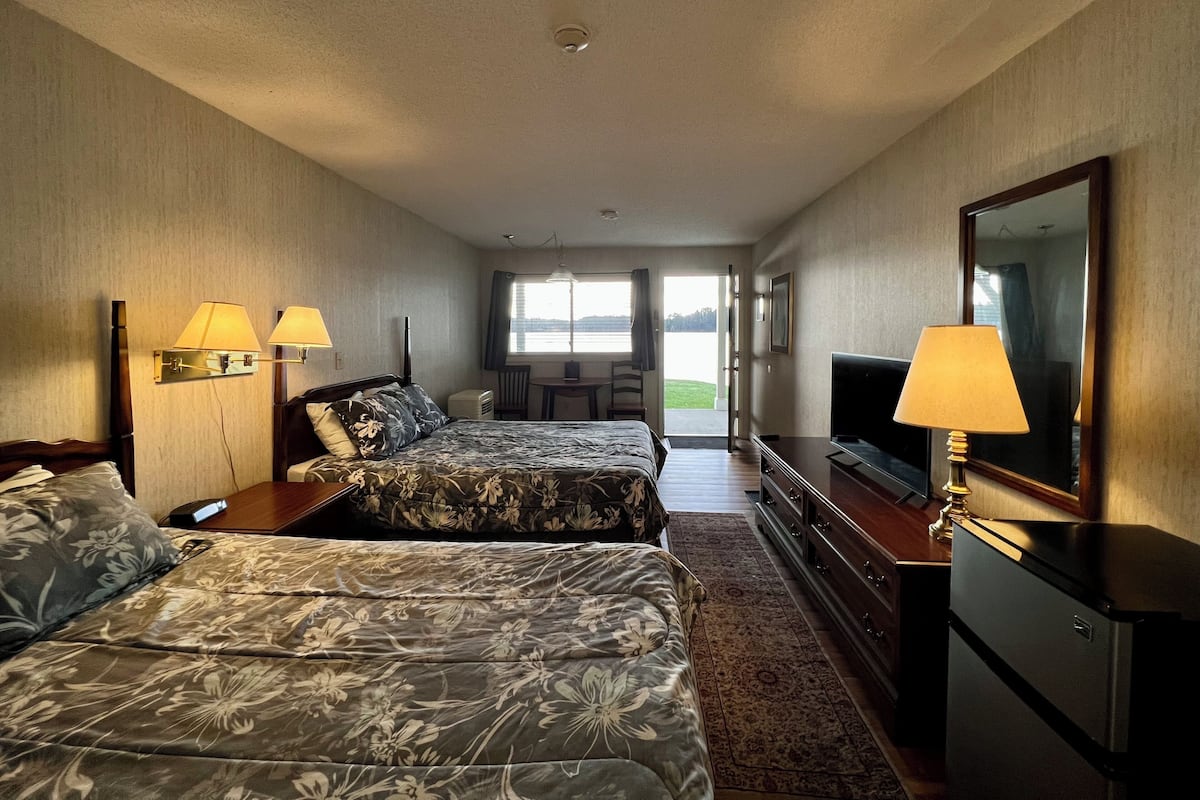 Une chambre d’hôtel avec deux lits, une télévision, un bureau et une vue sur l’extérieur.