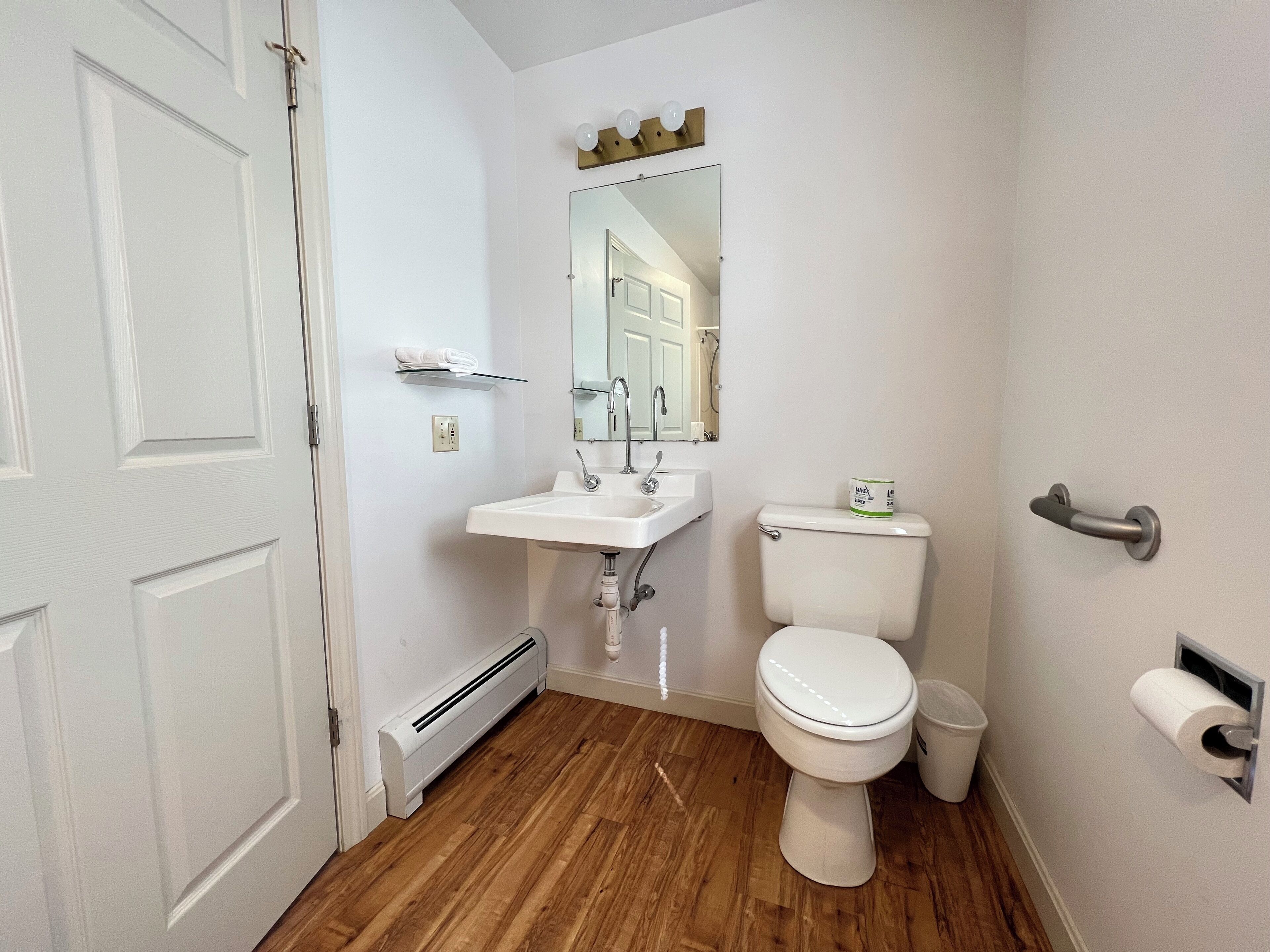 A bathroom with a white sink, toilet, and a mirror above the sink.