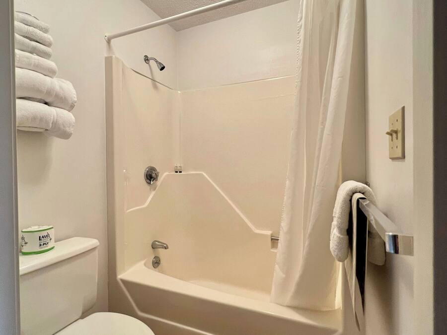 A bathroom with a shower, toilet, and a towel rack with towels.