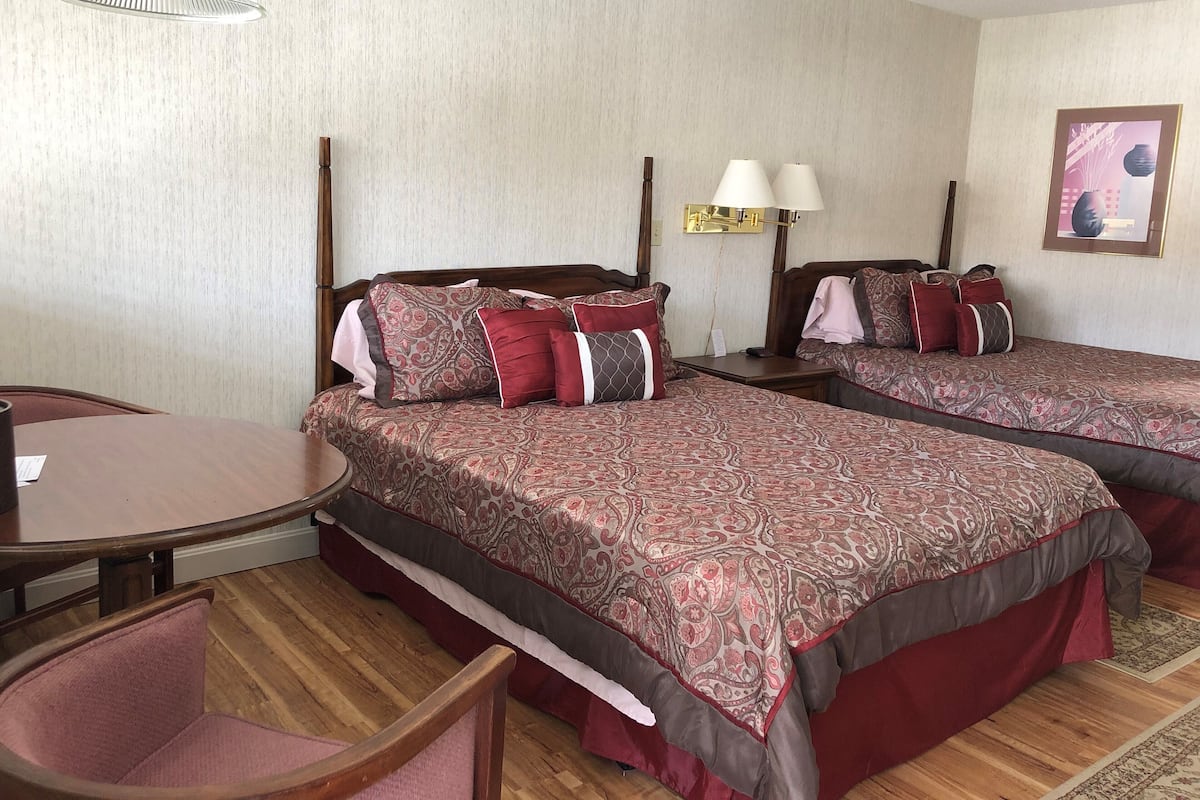 Une chambre d’hôtel avec deux lits, un plancher en bois, une table ronde et une chaise.