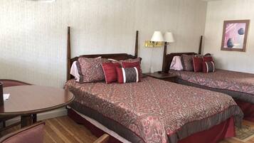 A hotel room with two beds, a wooden floor, a round table, and a chair.