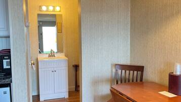 A compact kitchen with a refrigerator, sink, and a wooden dining table with chairs.