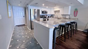 Cocina moderna con una isla central, electrodomésticos de acero inoxidable y una barra de desayuno con taburetes.