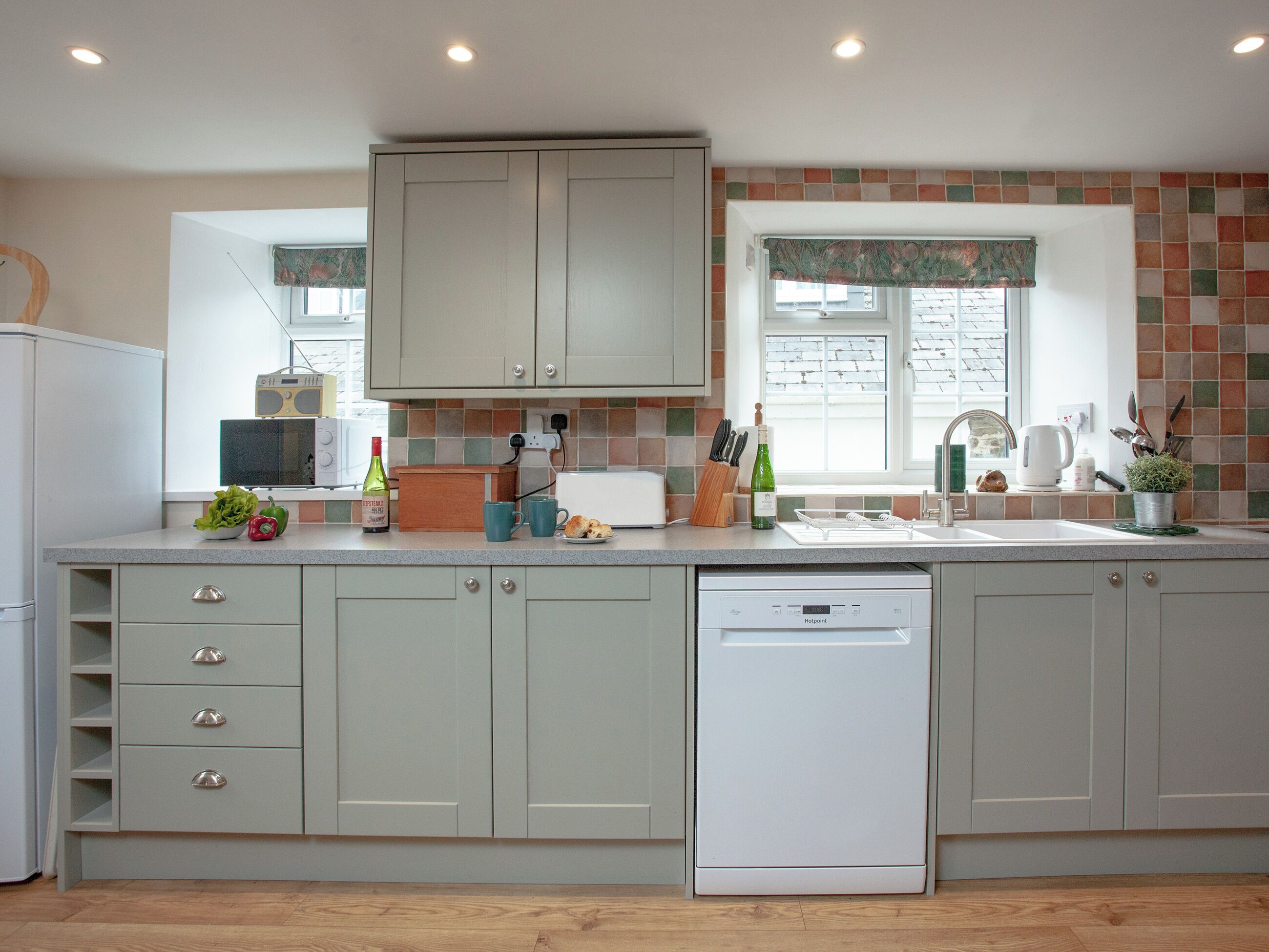 A kitchen with a dishwasher, a microwave, and a window with a view of the outside.