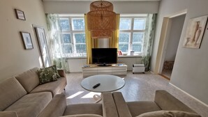 Una sala de estar con un sofá beige, una mesa de centro redonda y un televisor.