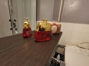 A bathroom with a wooden countertop, a white toilet, and a bottle of lotion.