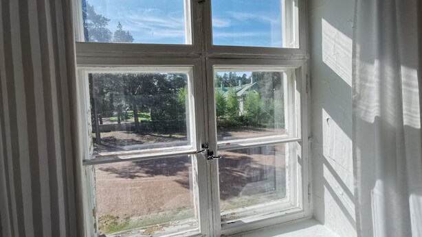 Ventana de cuatro paneles con vista a un parque y un edificio.