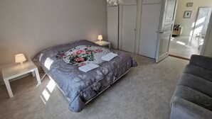 Un dormitorio con una cama, mesitas de noche, una silla y un armario.