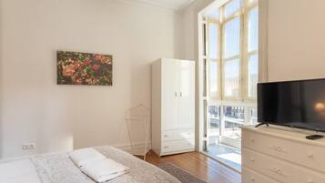 Un dormitorio con cama, televisor, armario y ventana con vistas.