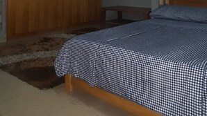Una camera da letto con un ampio guardaroba in legno, un letto con copriletto a quadretti e una tenda tartan.