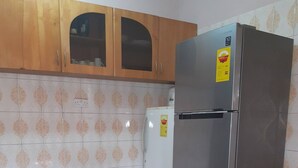 Una cucina con frigorifero in acciaio inossidabile, lavatrice bianca, mobili in legno e pareti rivestite di piastrelle decorate.