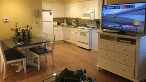 A compact kitchen with white cabinets, a microwave, and a stove. There's a dining table with chairs and a TV on a stand. - Hilton Head vacation resort: 2 blocks from the beach, near restaurants and golf! (Hilton Head Island)