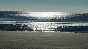 A beach with a clear sky and sunlight reflecting off the water. - Hilton Head vacation resort: 2 blocks from the beach, near restaurants and golf! (Hilton Head Island)
