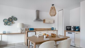 A modern kitchen with a wooden table, four chairs, a built-in oven, a microwave, and a coffee maker.