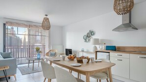 A modern kitchen with a dining area, featuring a wooden table, chairs, and a large window with a view of the city.