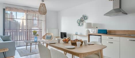 Eine moderne Küche mit Essbereich, ausgestattet mit einem Holztisch, Stühlen und einem großen Fenster mit Blick auf die Stadt.