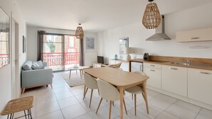 A modern kitchen with a dining table, chairs, and a large window.