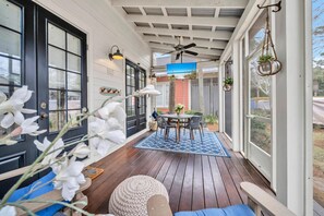 A covered porch with a wooden deck, a table with chairs, and a ceiling fan. - 🦩That's What Sea Shed! Sandestin Golf and Beach Resort ~ Golf Cart Included🦩 (Destin)
