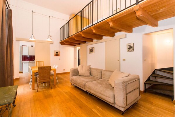 A living room with a sofa, dining table, chairs, and a staircase.