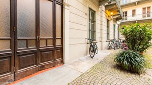 Un edificio con una puerta de madera grande, una bicicleta estacionada afuera y una planta en maceta.