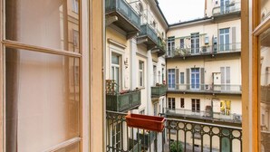 Un edificio de varios pisos con balcones, una ventana con marco de madera y una barandilla metálica.