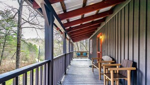 A covered wooden deck with benches and a railing, overlooking a forested area. - Fishin' Bear - Enjoy Spring and Summer in the Smokies! (Sevierville)