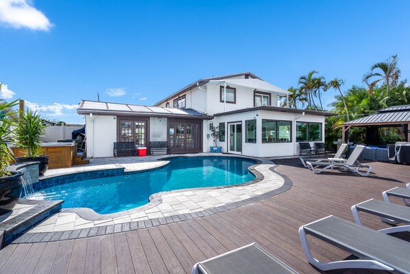 Una casa moderna con piscina, mobiliario exterior y terraza de madera.