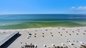 Une plage avec un long bâtiment, plusieurs chaises longues et une vue dégagée sur l’océan.
