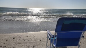 Una silla de playa mirando al océano, con olas rompiendo en la orilla.