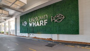 A building entrance with a green wall displaying 'Laketown WHARF' and two logos. - 'Ocean Oasis' PCB Condo w/ Balcony & Beach Views! (Panama City Beach)