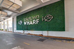 Entrada de un edificio con un muro verde que muestra 'Laketown WHARF' y dos logotipos.