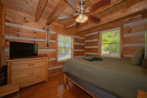 A wooden cabin room with a bed, a dresser, a television, and a ceiling fan. - Cabin of Dreams Beautiful Mountain Views • Hot Tub • Near Dollywood & Gatlinburg (Pigeon Forge)