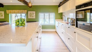 A kitchen with a large island, white cabinetry, and a green accent wall.