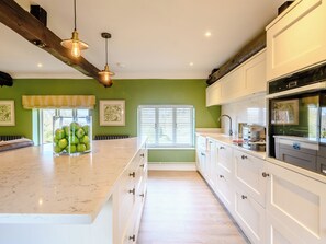 A kitchen with a large island, white cabinets, and a green wall.