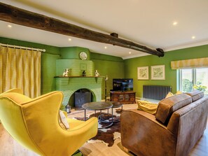 A living room with a fireplace, green walls, and a wooden ceiling beam.