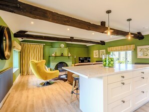 Una cocina con encimera de mármol, vigas de madera, una silla amarilla y una chimenea.