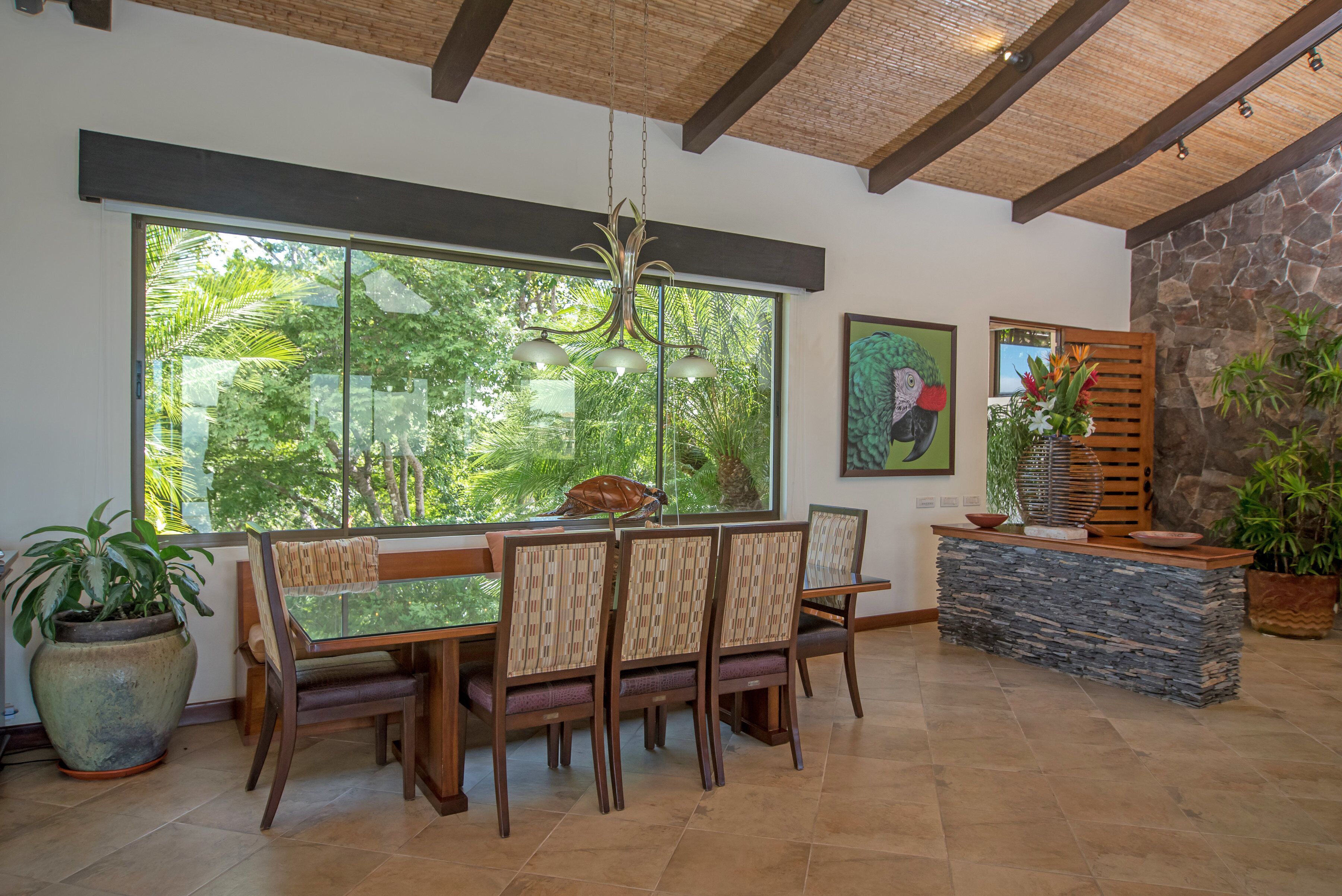 A dining area with a large window, a stone accent wall, and a hanging light fixture.