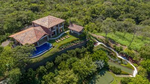 A large house with a swimming pool, surrounded by lush greenery and a golf course. - Villa Costa Mar Ocean View Guard Gated Community (Playa Hermosa, Carrillo)