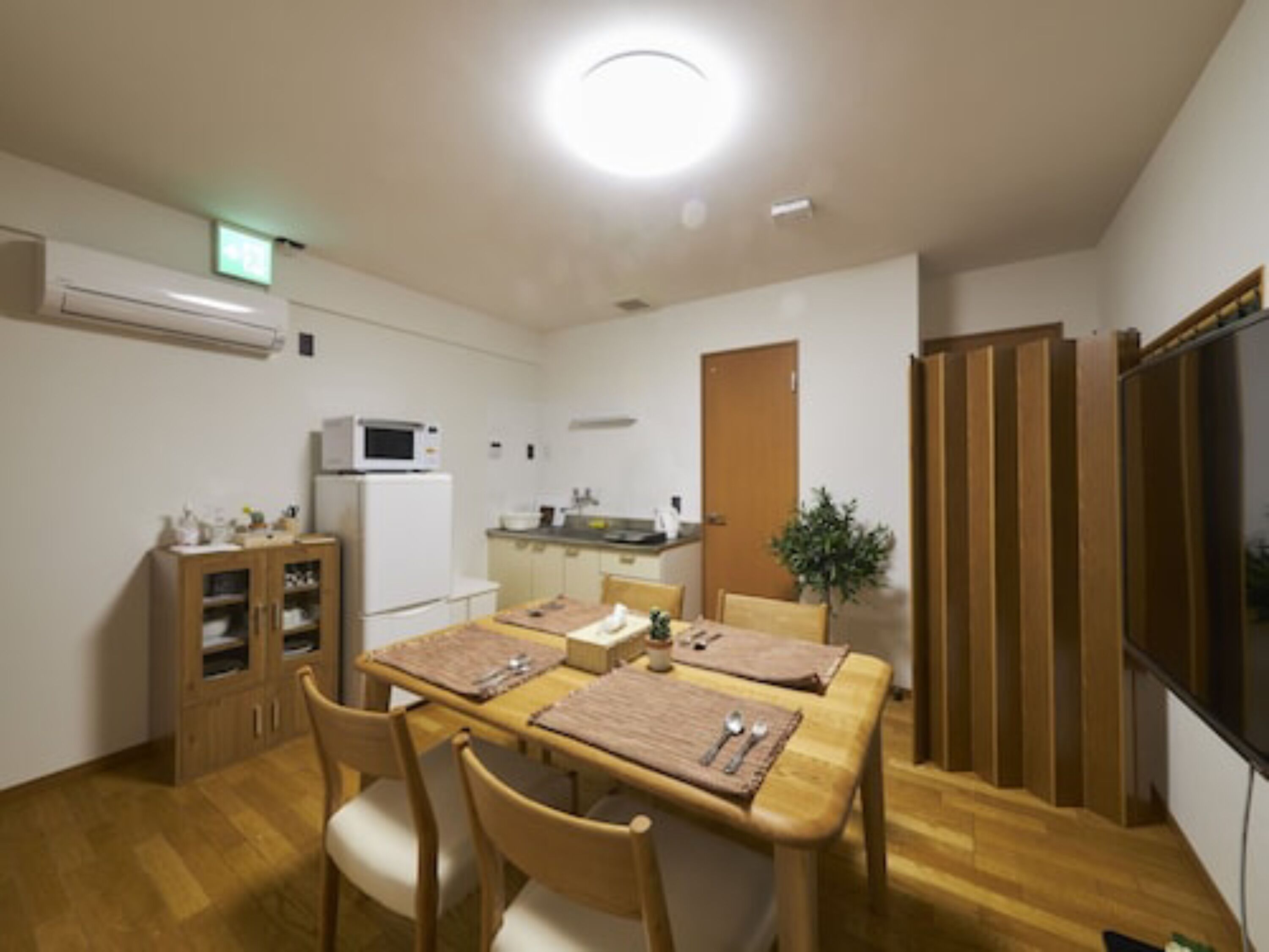 Una cocina compacta equipada con microondas, refrigerador y un pequeño comedor con mesa y sillas.