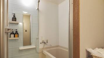 A bathroom with a shower, a bathtub, and a mirror. There are two bottles on a shelf.