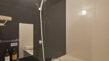 A modern bathroom with a bathtub, a shower, and a mirror.