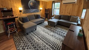 A cozy living room with a sectional sofa, a coffee table, and a ceiling fan.